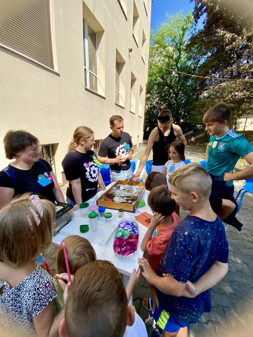 Stolik pokazowy, organizatorzy ŚFN on Tour i dzieci oglądające czaszki zwierząt | Fot. Paulina Świtała