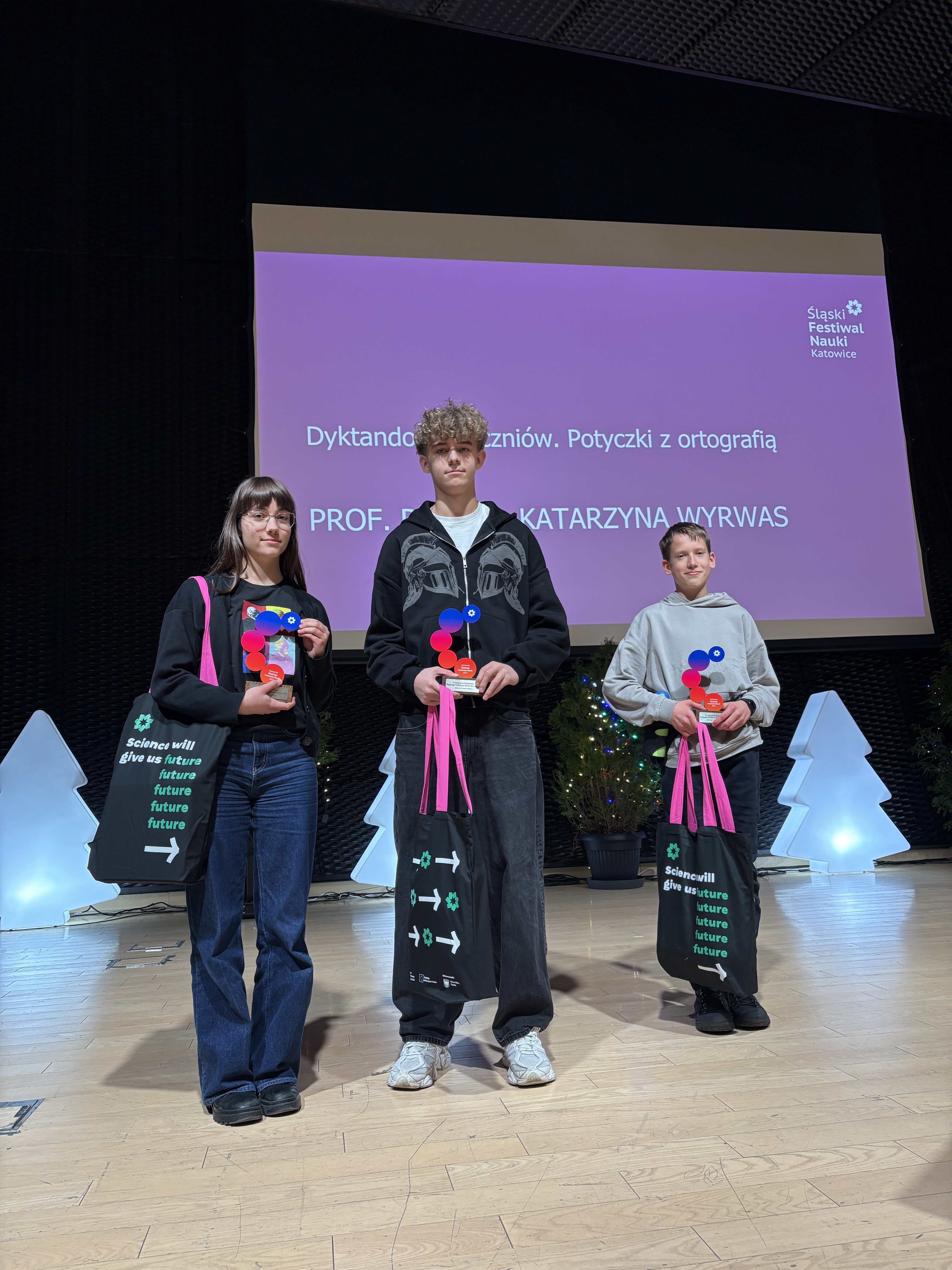 Uczestnicy siedzący przy stołach i piszący dyktando na kartkach