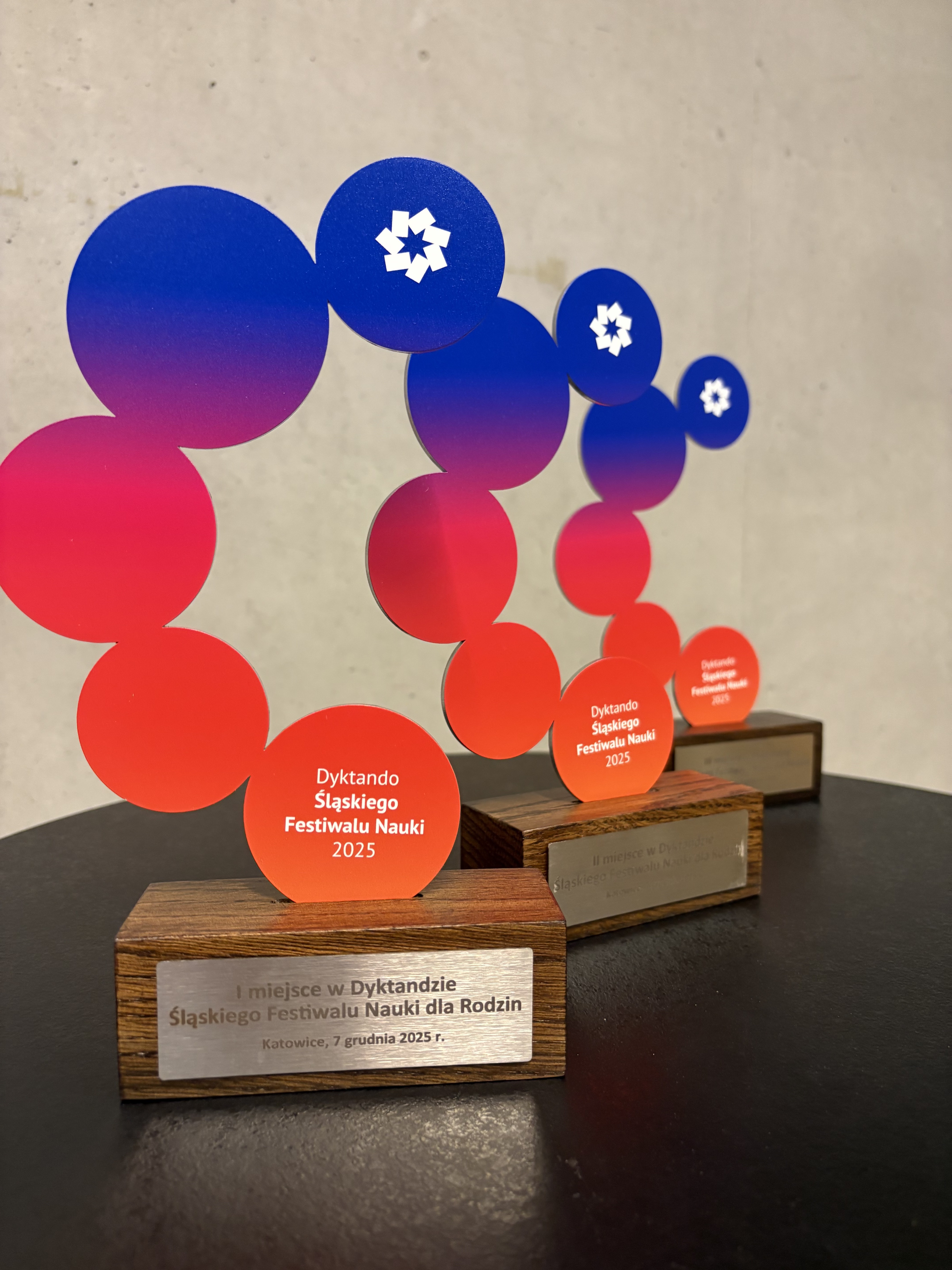 Widok sali z rzędami stołów i uczestnikami dyktanda