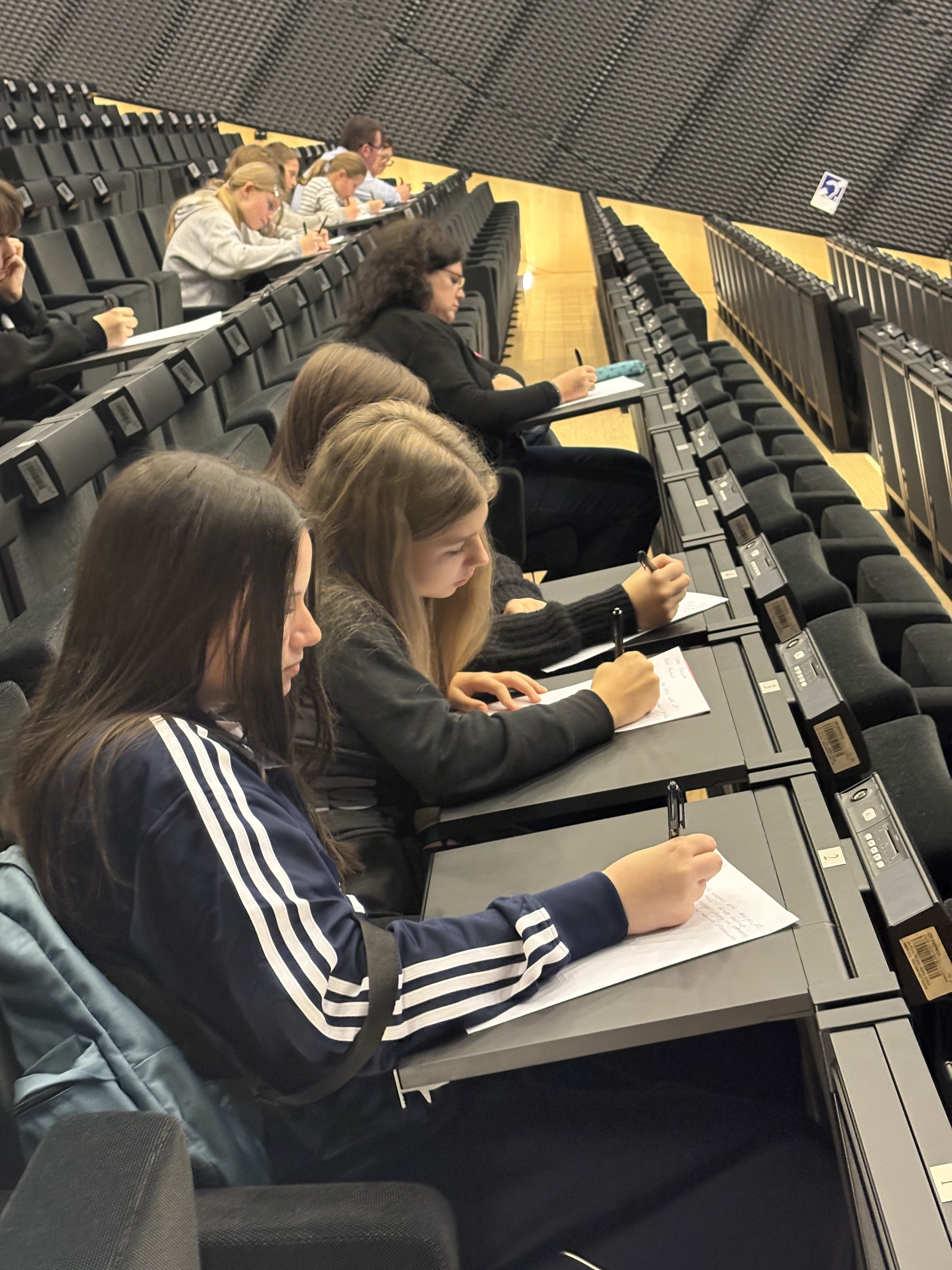 Uczestnicy dyktanda siedzący przy stołach w dużej sali