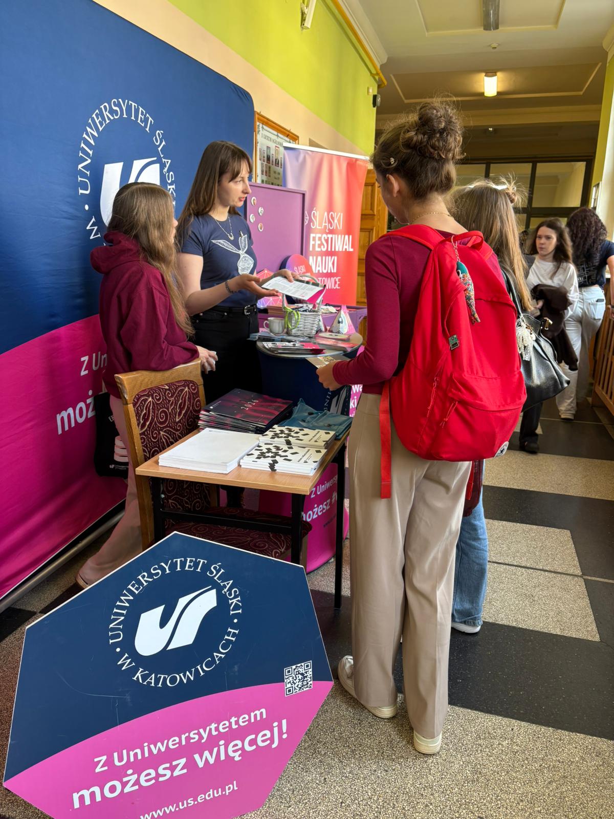 Stoisko ŚFN w szkole, logotypy ŚFN i UŚ na bannerach