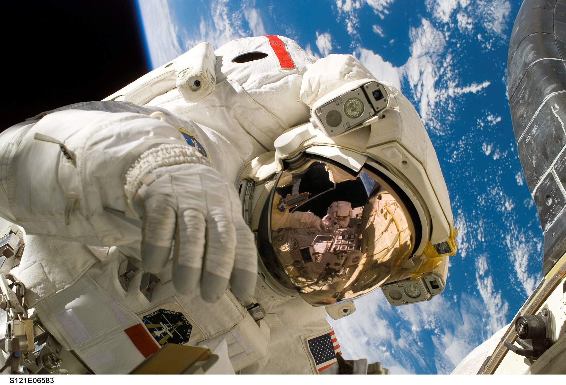 Astronauta przebywający w przestrzeni kosmicznej, w tle planeta Ziemia