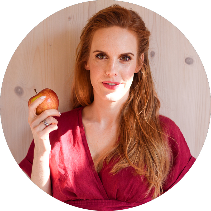 Bohaterka wywiadu ubrana w ciemnoróżową suknię trzyma w prawej ręce czerwone jabłko